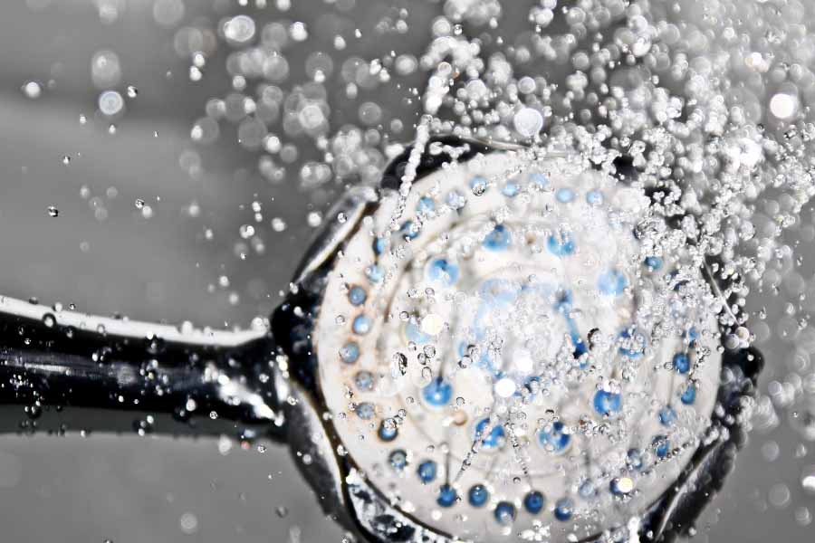 Ingezoomde douche kop met stromend water. Douchekop is zichtbaar smerig.