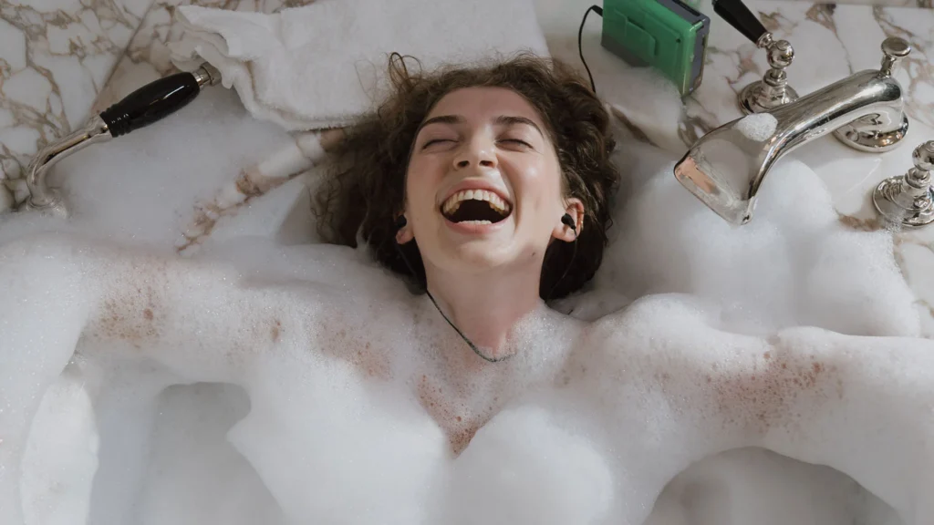 Dame licht stralend in bad met veel schuim luisterend naar muziek